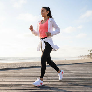 FWSports Shoes Glycerin Max 2 running shoes in white and orange worn by a woman jogging on a wooden boardwalk.