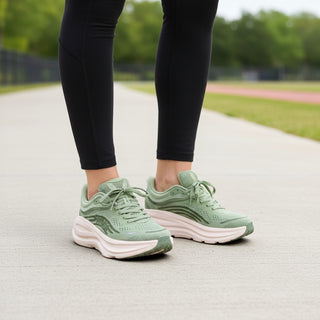 FWSports Shoes Womens Hoka Bondi 9 running shoes in sage green with thick cushioned soles worn on a paved track