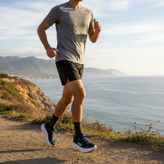 A runner wearing FWSports Shoes Hoka Bondi 9 naval blue sneakers with plush cushioning on a coastal trail.