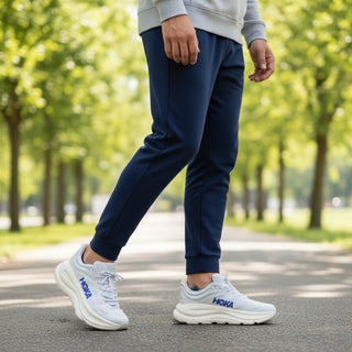 FWSports Shoes Hoka Bondi 9 running shoes in white and blue worn by a man in navy joggers on a park path