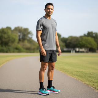 A man wearing FWSports Shoes Hoka Clifton 8 running shoes in real teal and aquarelle on a paved outdoor track.