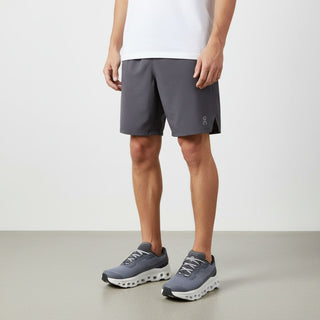 FWSports Shoes model wearing grey athletic shorts and On Running Cloudmonster sneakers in lime and glacier ash.