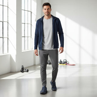 Man wearing FWSports Shoes blue On Running Cloudmonster Void sneakers with a navy jacket and grey trousers in a gym