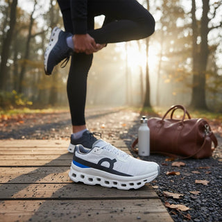 FWSports Shoes Womens On Running Cloudmonster Void in white and gray mesh with oversized cushioning on a wooden path.