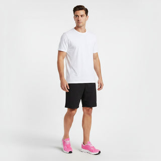 A man wearing FWSports Shoes On Cloud 6 waterproof sneakers in bright pink with a white t-shirt and black shorts.