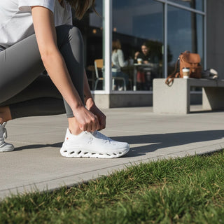 FWSports Shoes Womens On-Run Cloudtilt all white sneakers with mesh upper and rocker sole being laced up outdoors